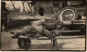A terribly stark contrast between the poor man/beggar on his wheelbarrow and the modern de luxe car behind him.